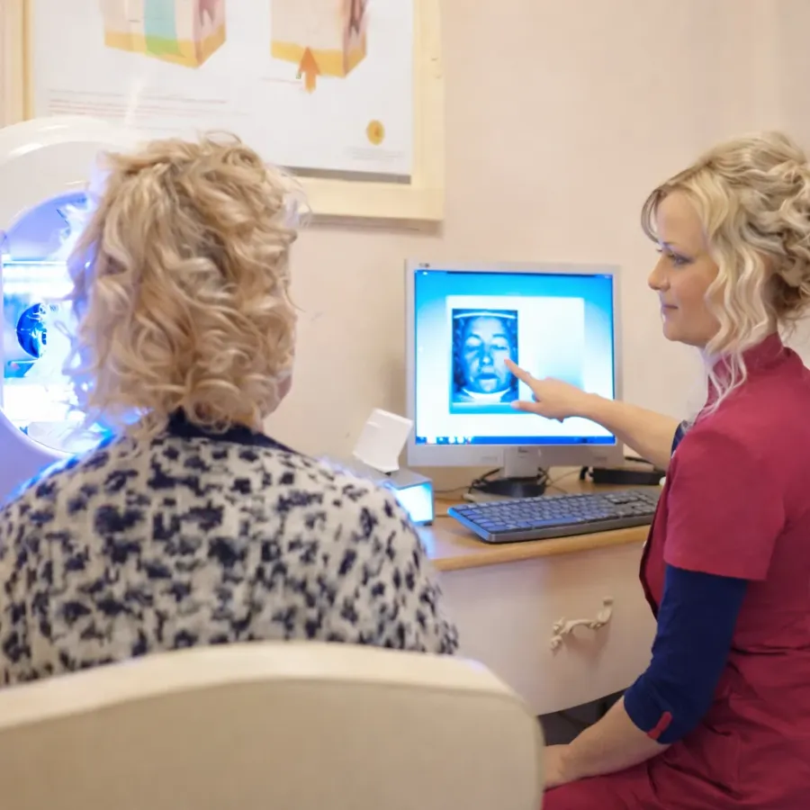 Carinda bespreekt de huidscan met een klant op het scherm.